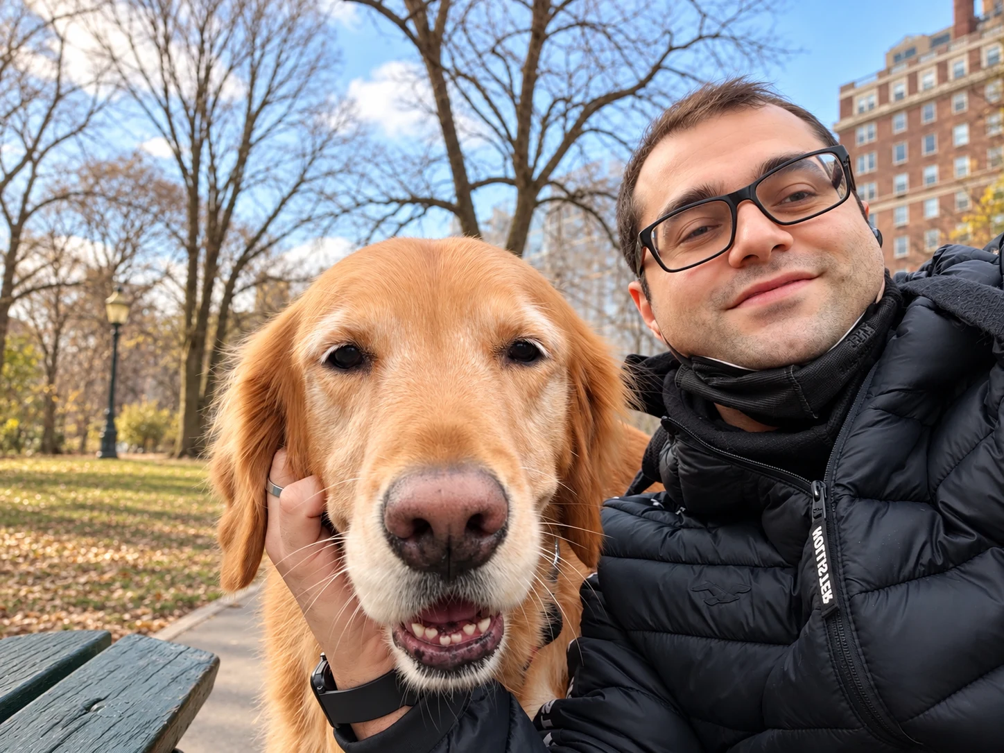 Senator sitting on a park bench beside a person, with bare winter trees behind them.